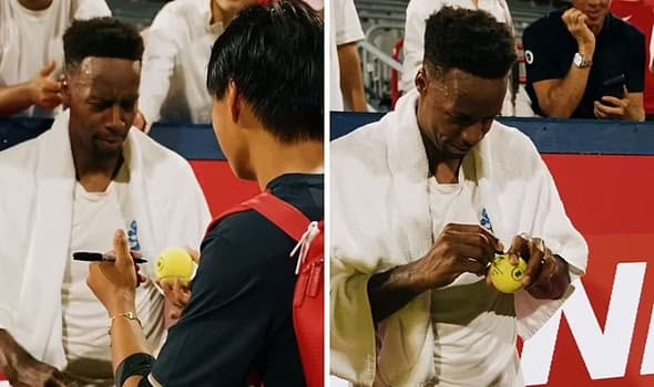 Learner signs autographs courtside in a white shirt, smiling while interacting with fans at the court barrier.